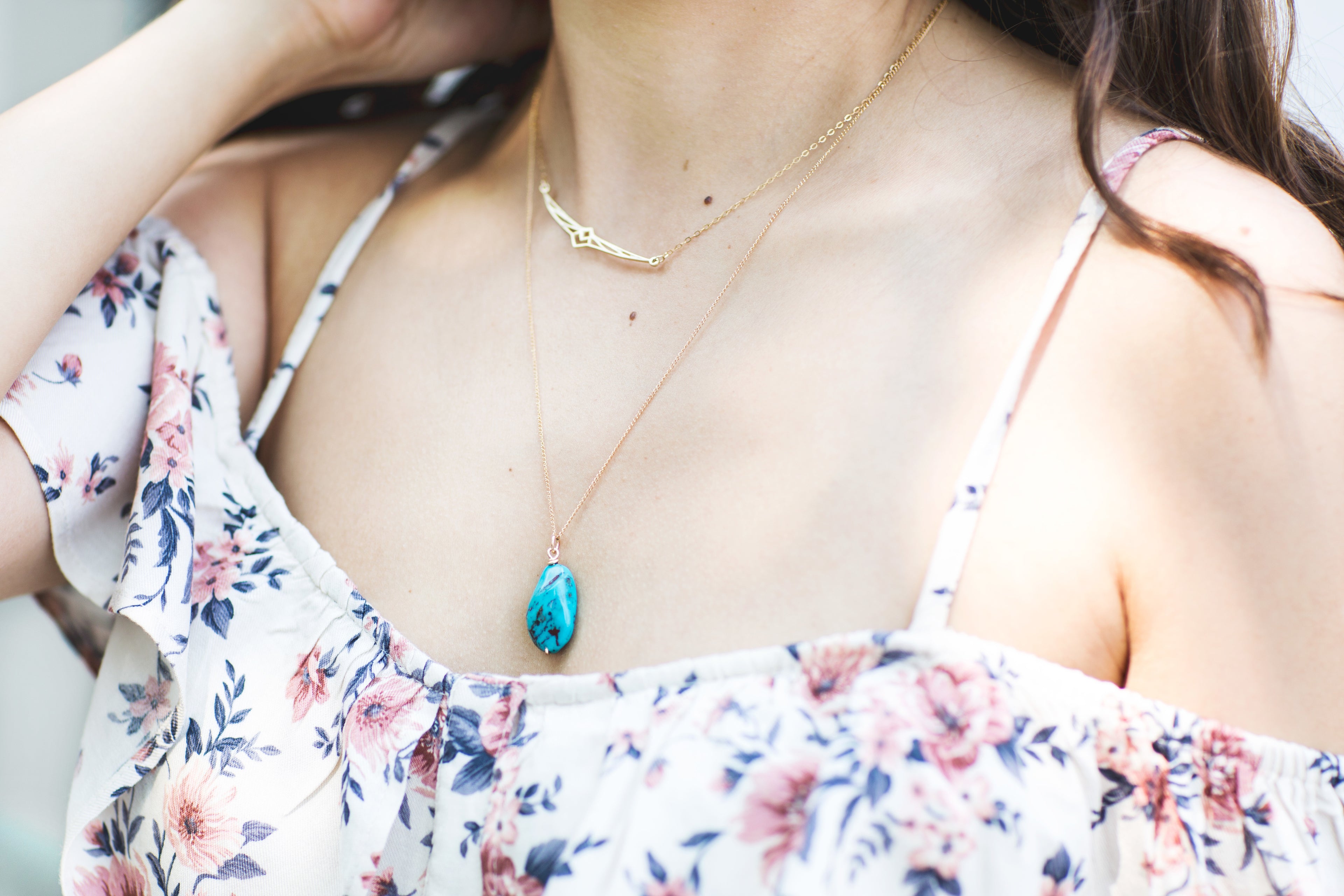 Female wearing  stone necklace and floral dress 